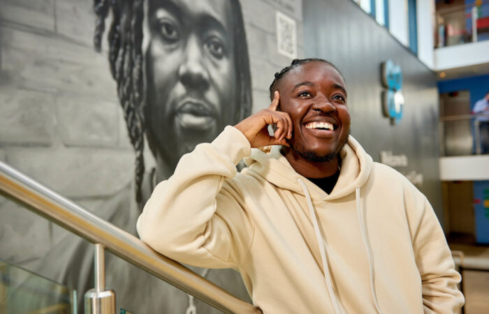 The Passing of Melz Owusu Melz in front of the co-op mural of them