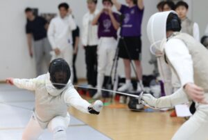 Two fencers mid-bout in a sports hall
